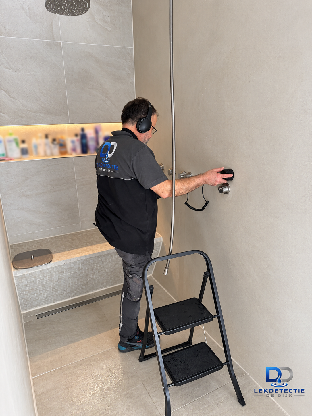 Monteur meet aan de wand bij de douche — omslagfoto van project Villa Lek